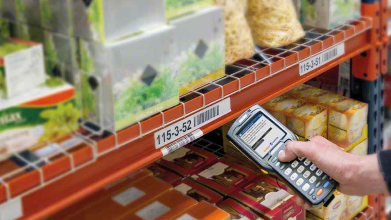 Trabajador revisando el inventario de productos en un almacén con un lector de códigos