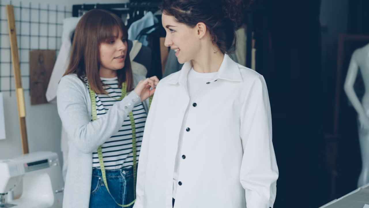 Profesional tomando medidas de una camisa sobre una mujer en un taller.