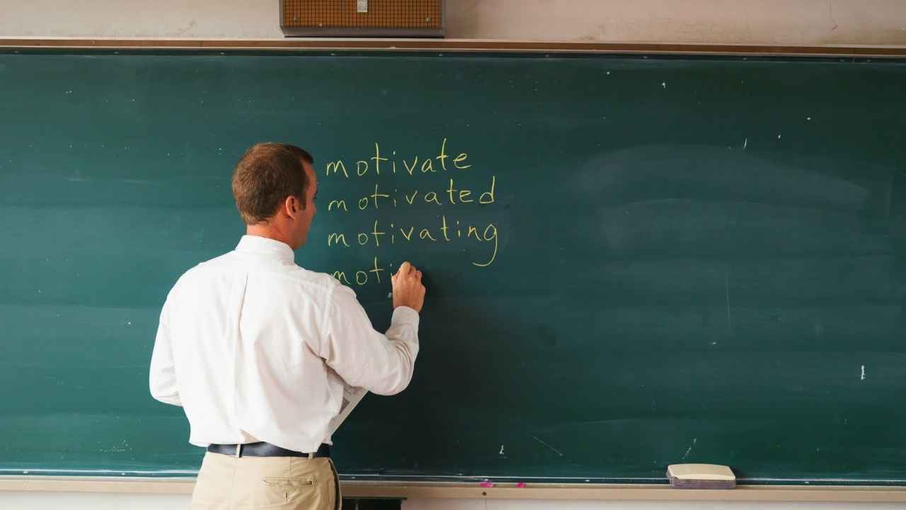 Profesor escribiendo en una pizarra durante una clase en un centro educativo.