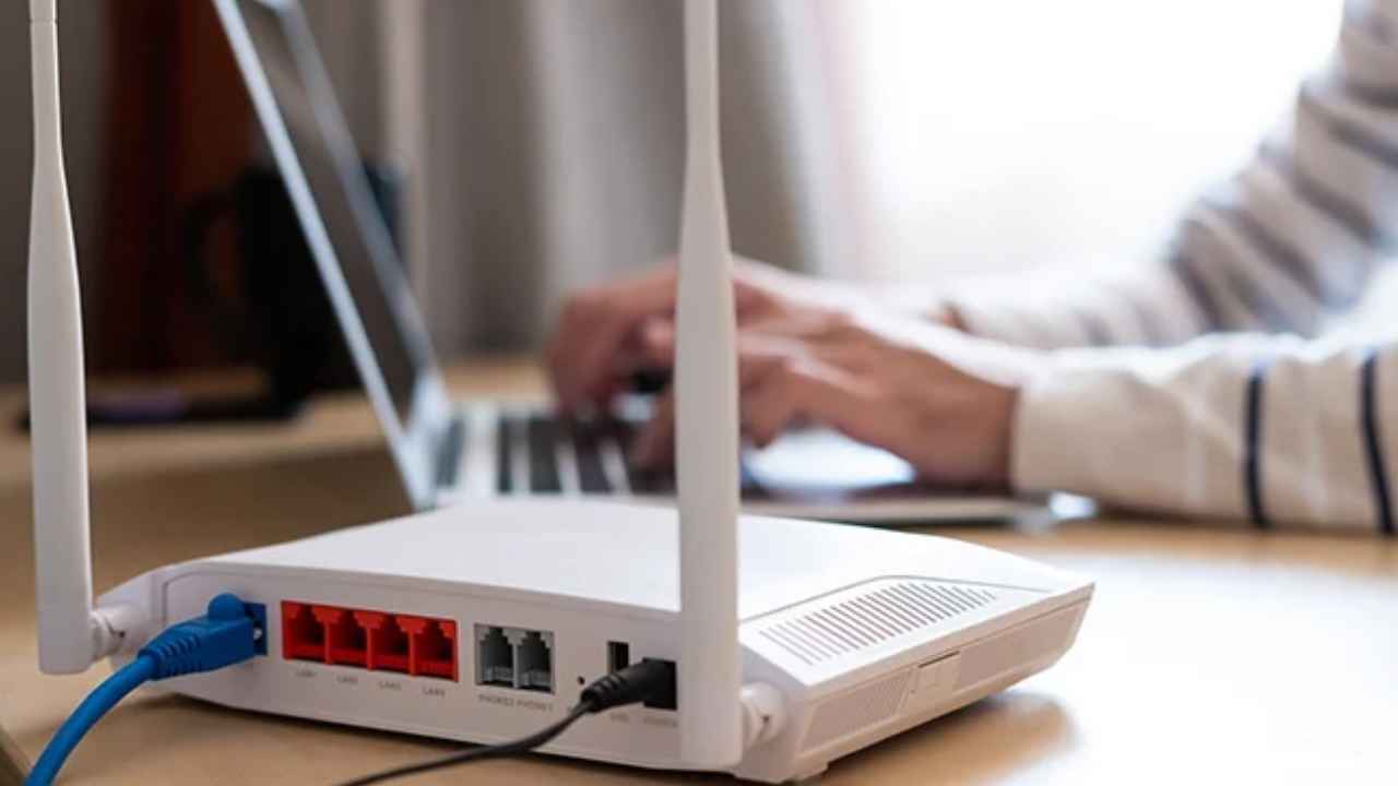 Router doméstico conectado mientras una persona usa un ordenador portátil