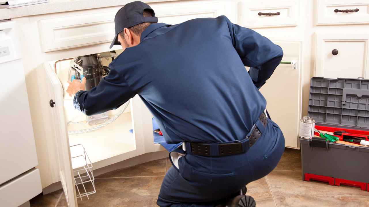 Fontanero trabajando en la instalación bajo el fregadero de una cocina