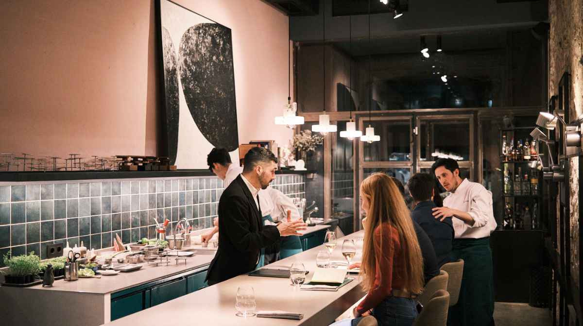 Interior de un restaurante gastronómico con cocina abierta y comensales en la barra