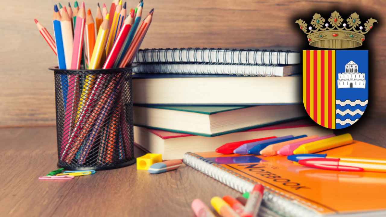Material escolar con lápices de colores, cuadernos, libros y rotuladores sobre una mesa de madera.