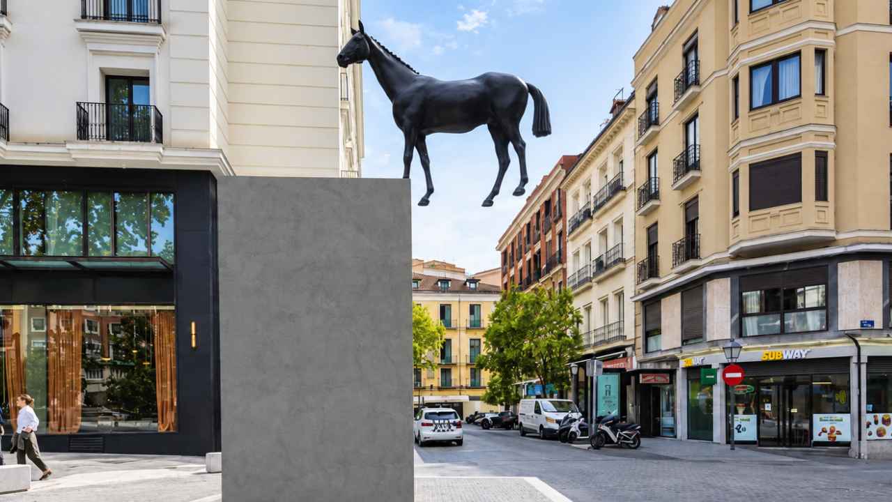 Caballo de bronce sin jinete apoyado sobre un extremo del pedestal en la plaza del Carmen de Madrid