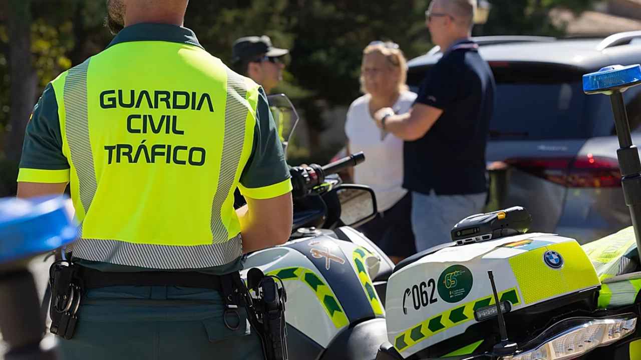 Agente de la Guardia Civil de Tráfico junto a varias motocicletas oficiales durante un control de carretera.