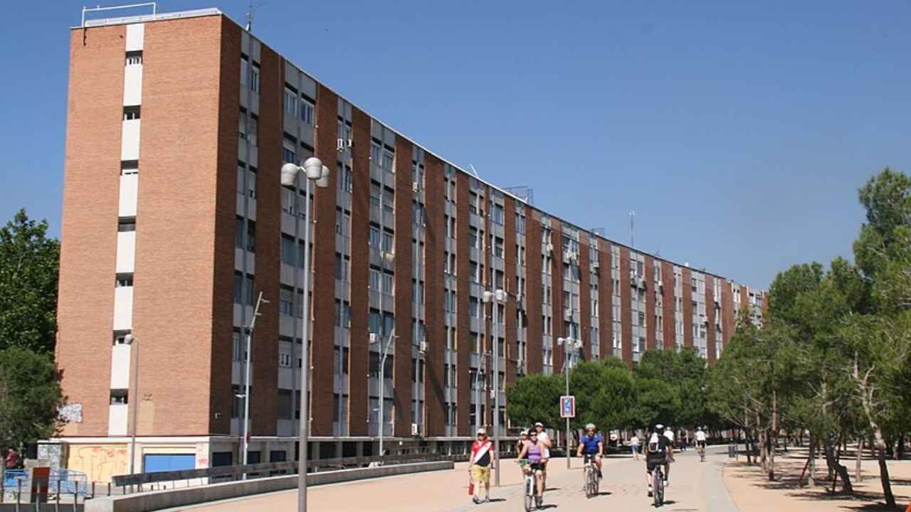Fachada de un bloque de viviendas de ladrillo junto al paseo arbolado de Madrid Río.