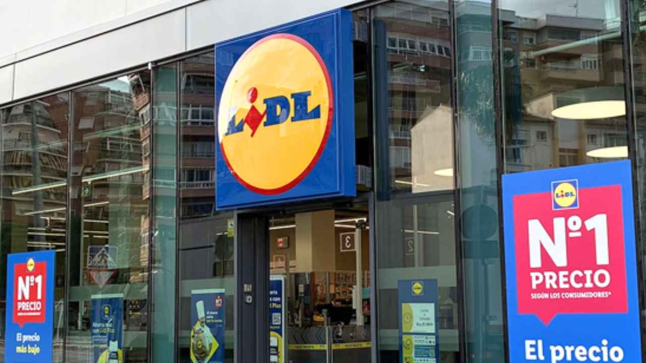 Fachada de un supermercado Lidl con entrada acristalada, logotipo y carteles promocionales.