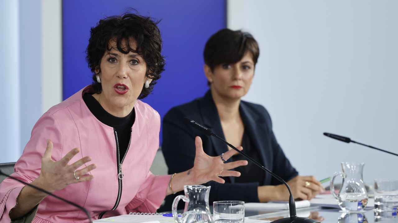 Rueda de prensa del Gobierno de España con dos representantes institucionales ante el cartel de Acción de Gobierno.
