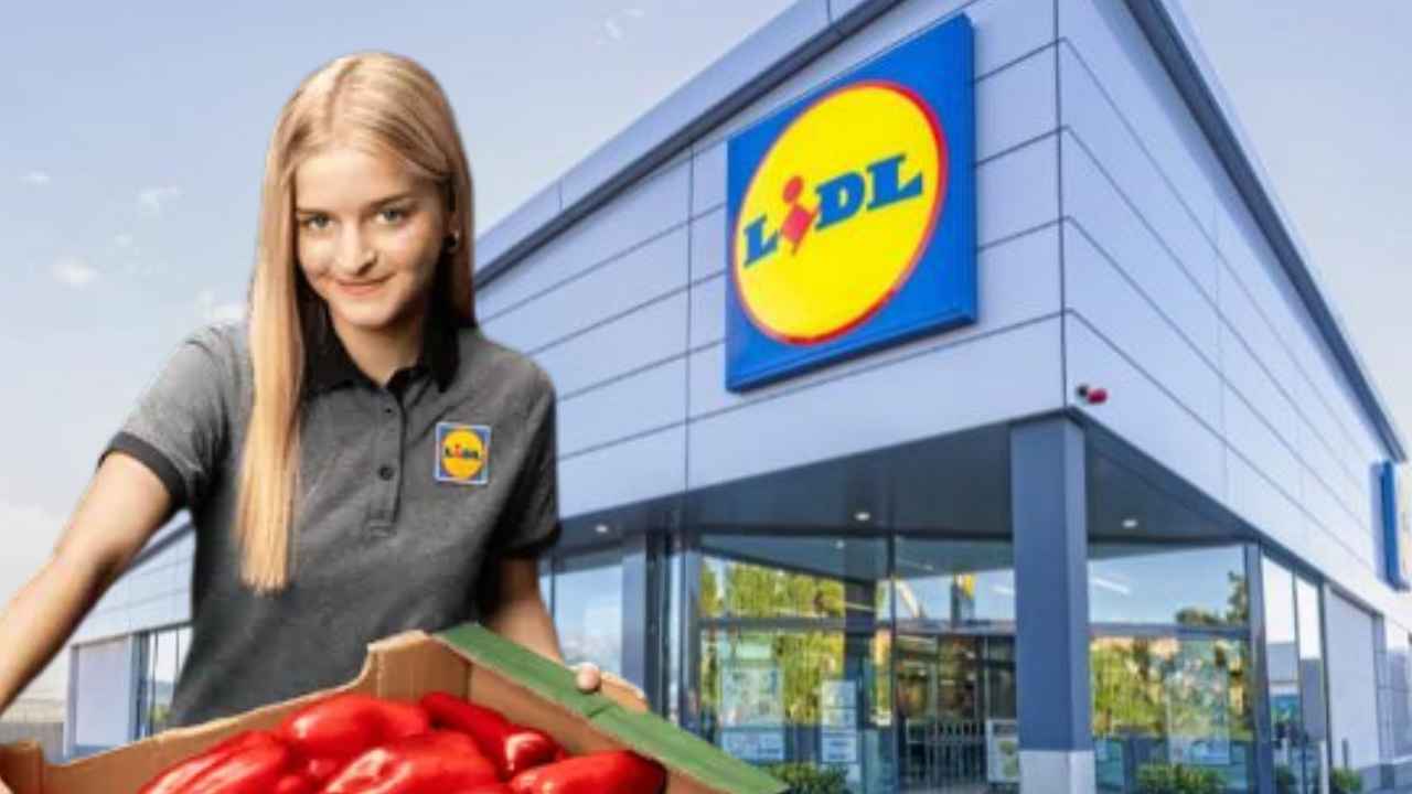 Trabajadora de Lidl con una caja de pimientos rojos delante de un supermercado de la cadena.