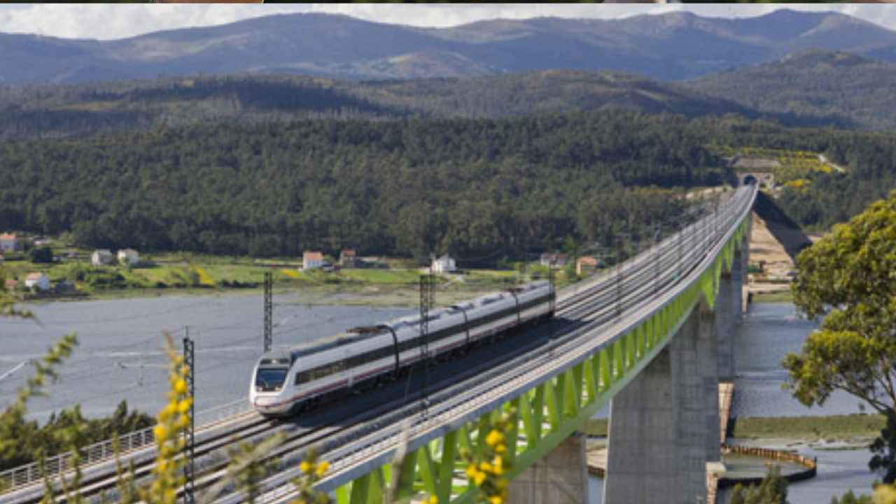 Tren de Renfe circulando por un viaducto ferroviario sobre una ría gallega, rodeado de montañas y vegetación.