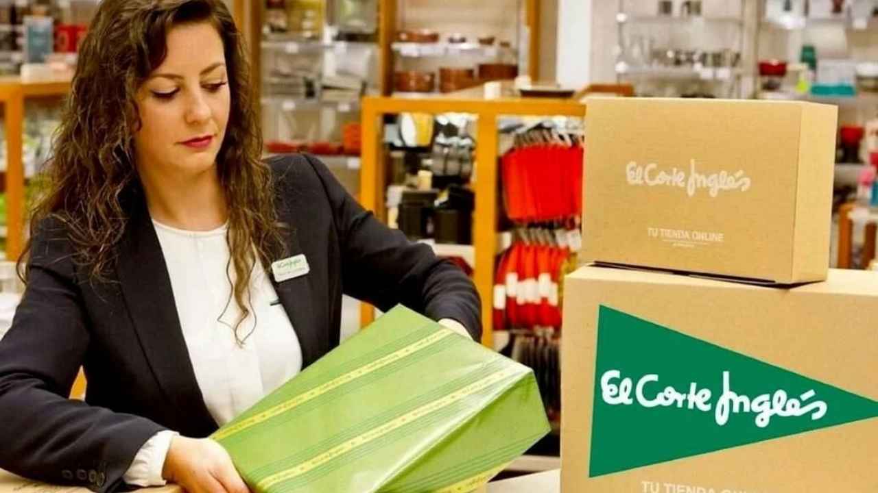 Dependienta de El Corte Inglés preparando un paquete en el mostrador junto a varias cajas de la empresa.