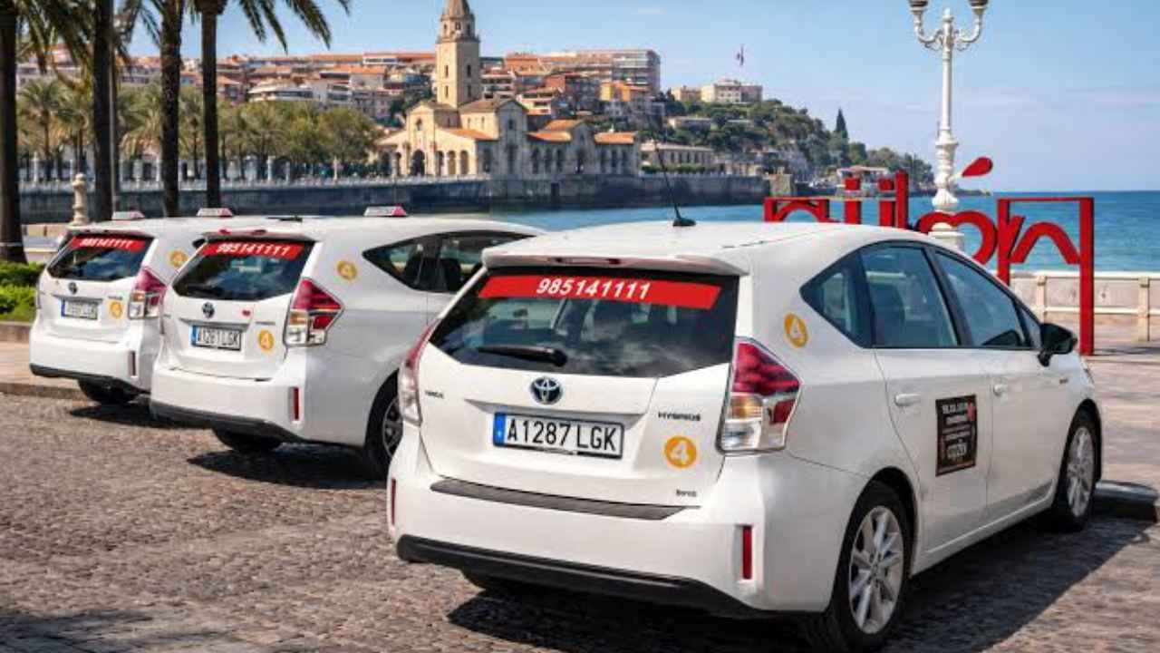 Varios taxis blancos estacionados junto al paseo marítimo de Gijón, Asturias.